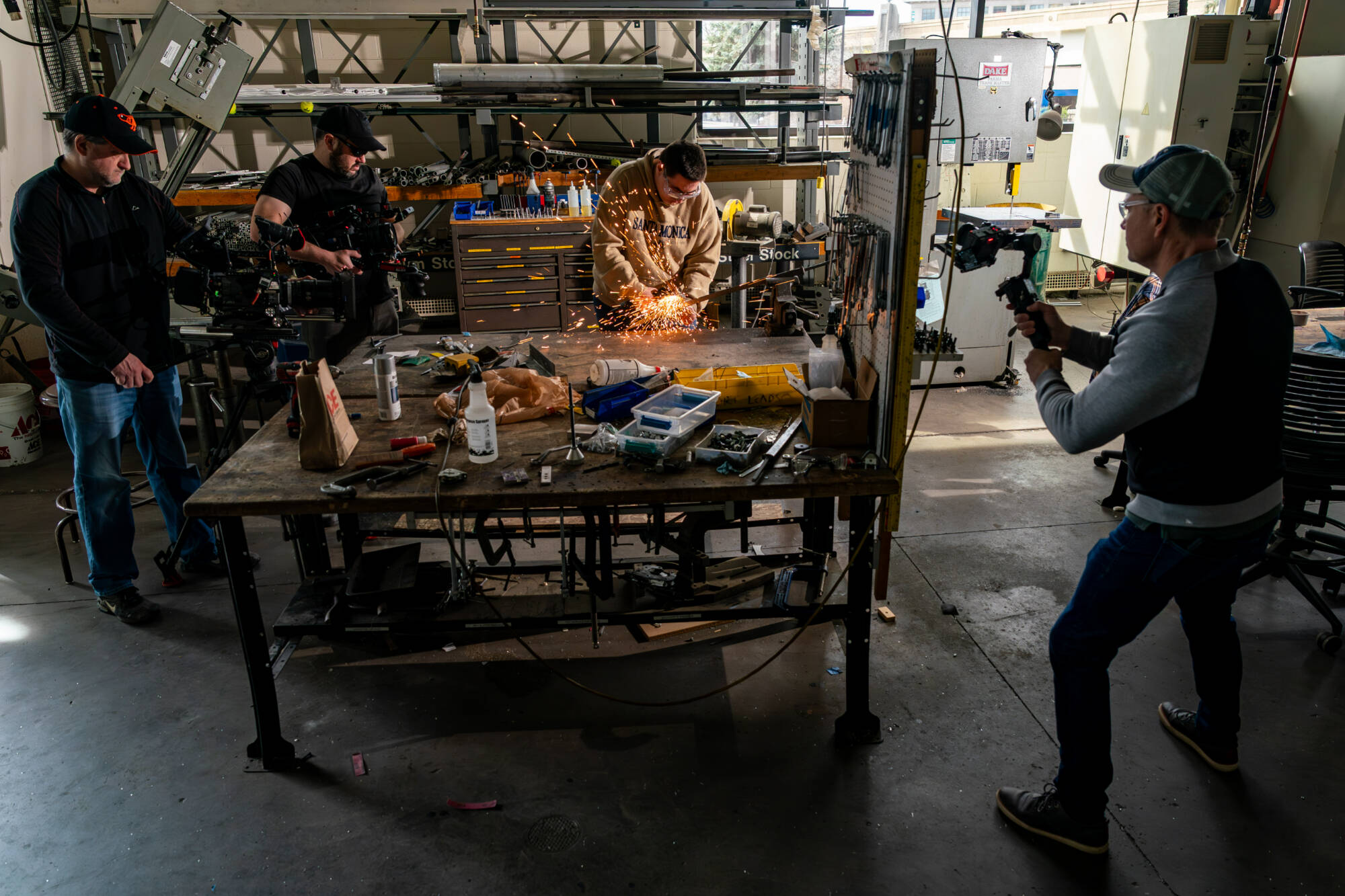 Sparks fly as mechanical engineering major Scott Strayer, center, grinds a sword for a video crew at the Kennedy Hall of Engineering on March 21. Workaholic Productions is producing a video of GVSU students making a sword for the Cast in Steel competit...